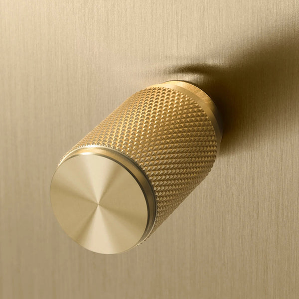 Close up of a brass knob with a textured surface and a smooth, reflective end