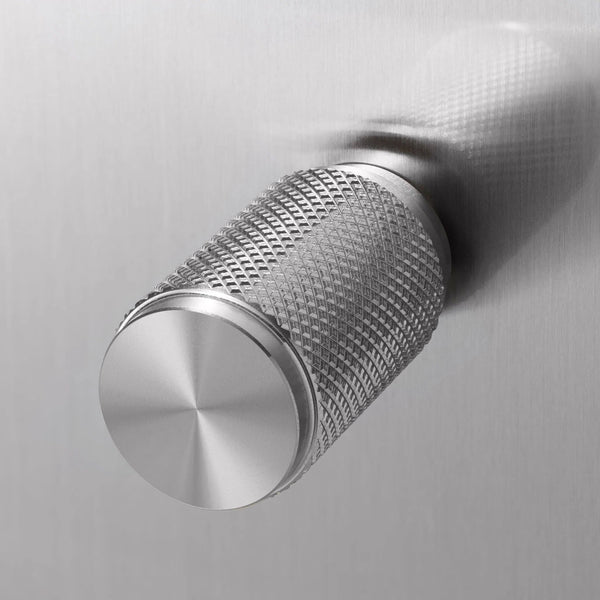 Close up of a silver metal knob with a diamond pattern texture