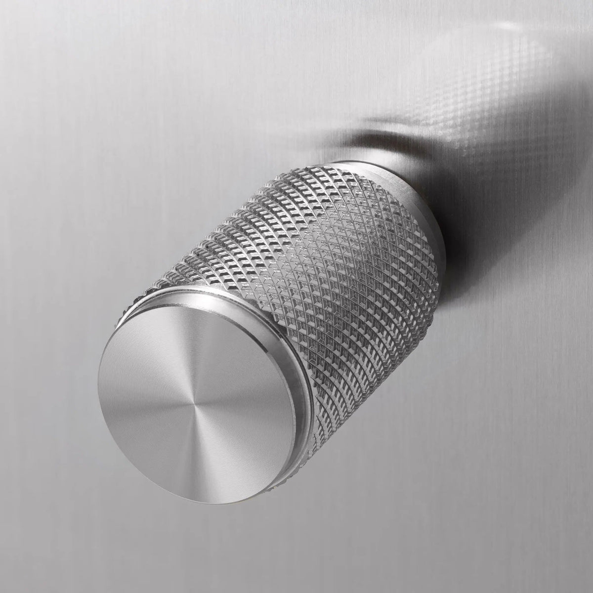 Close up of a silver metal knob with a diamond pattern texture