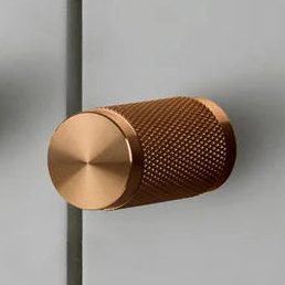 Knurled solid copper cabinet knob on a grey cabinet