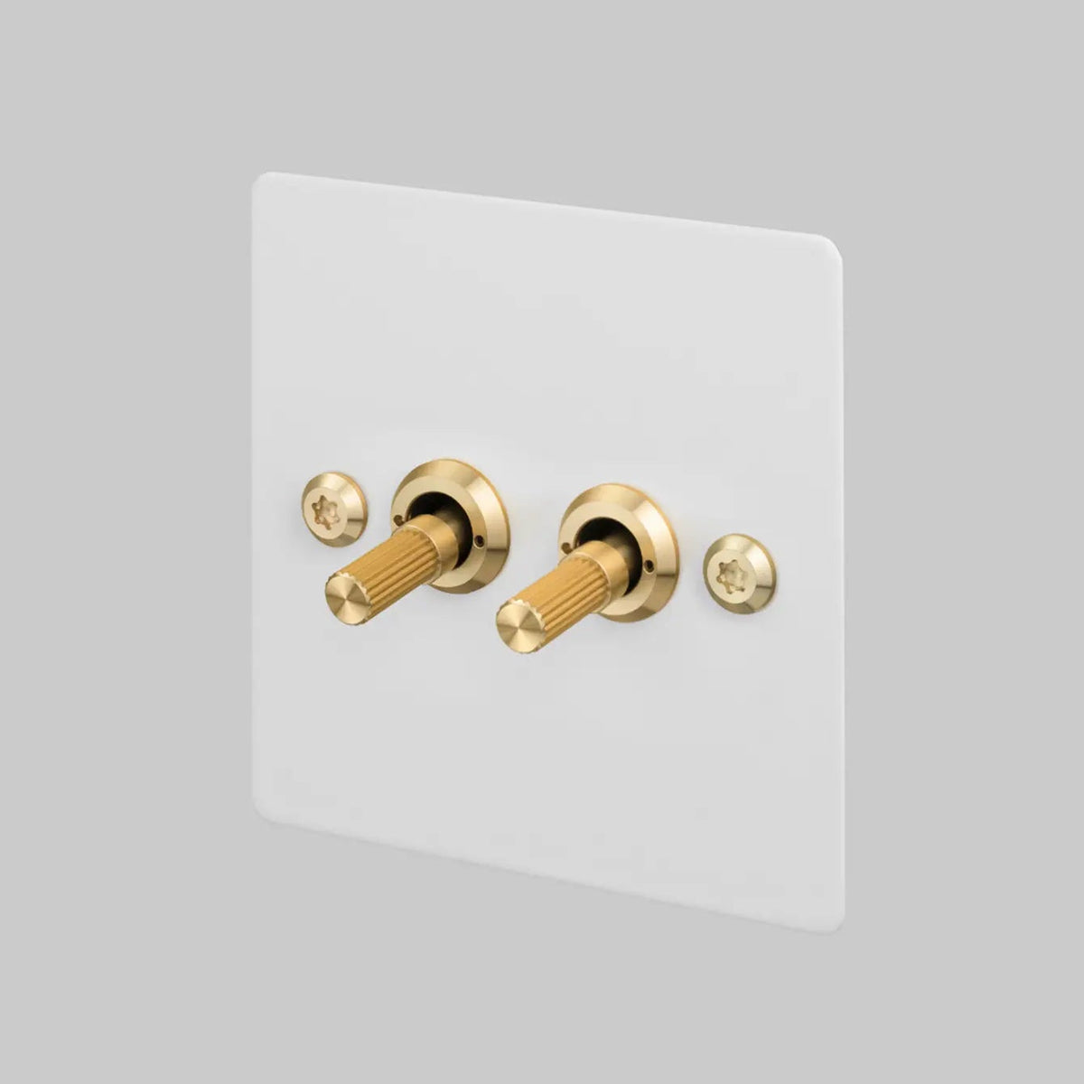 Buster and Punch two gang two way light switch in white with brass linear knurled toggles