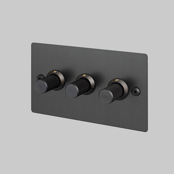 Three black dimmer switches with gold markings on a rectangular black plate