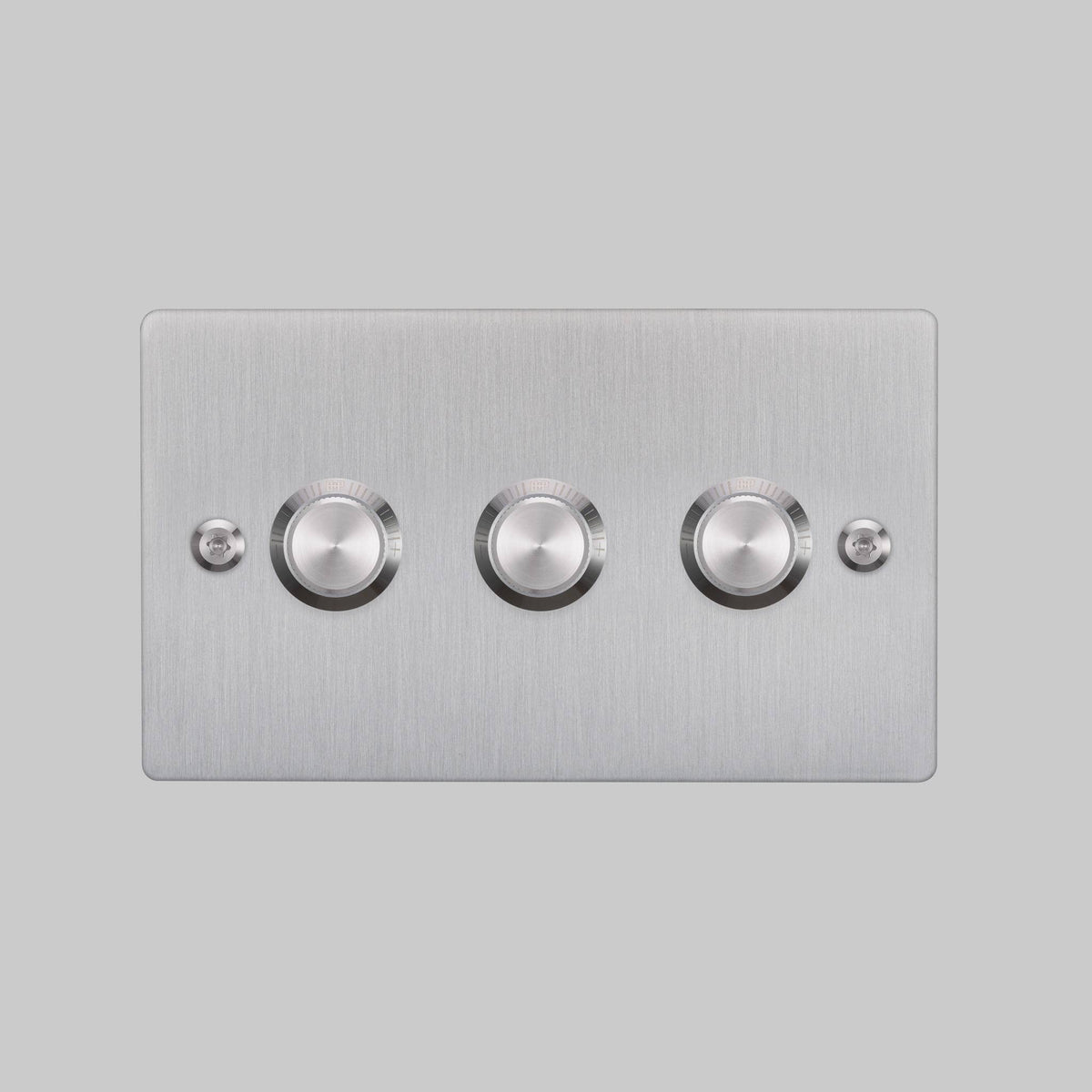 Brushed steel triple dimmer switch with three rotary controls and two small screws on a light grey background