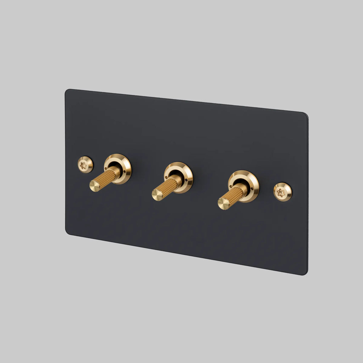 Buster and Punch three gang two way light switch with black plate and brass linear knurled toggles