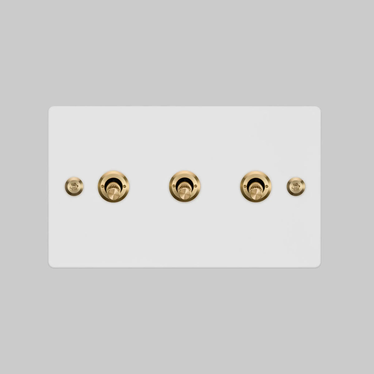 Buster and Punch three gang two way light switch in white with brass linear knurled toggles