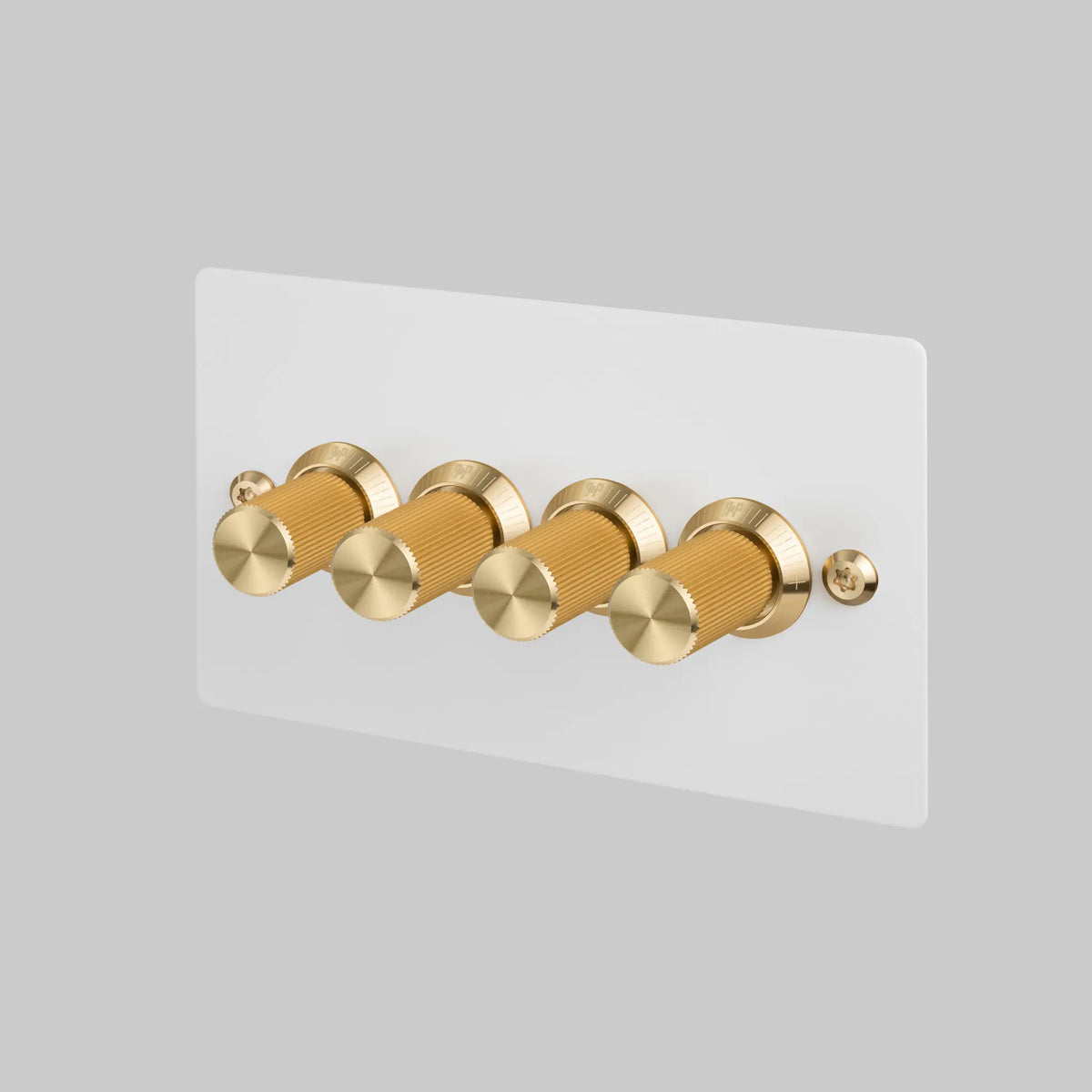 Four gold knurled rotary dimmer knobs on a white rectangular wall plate