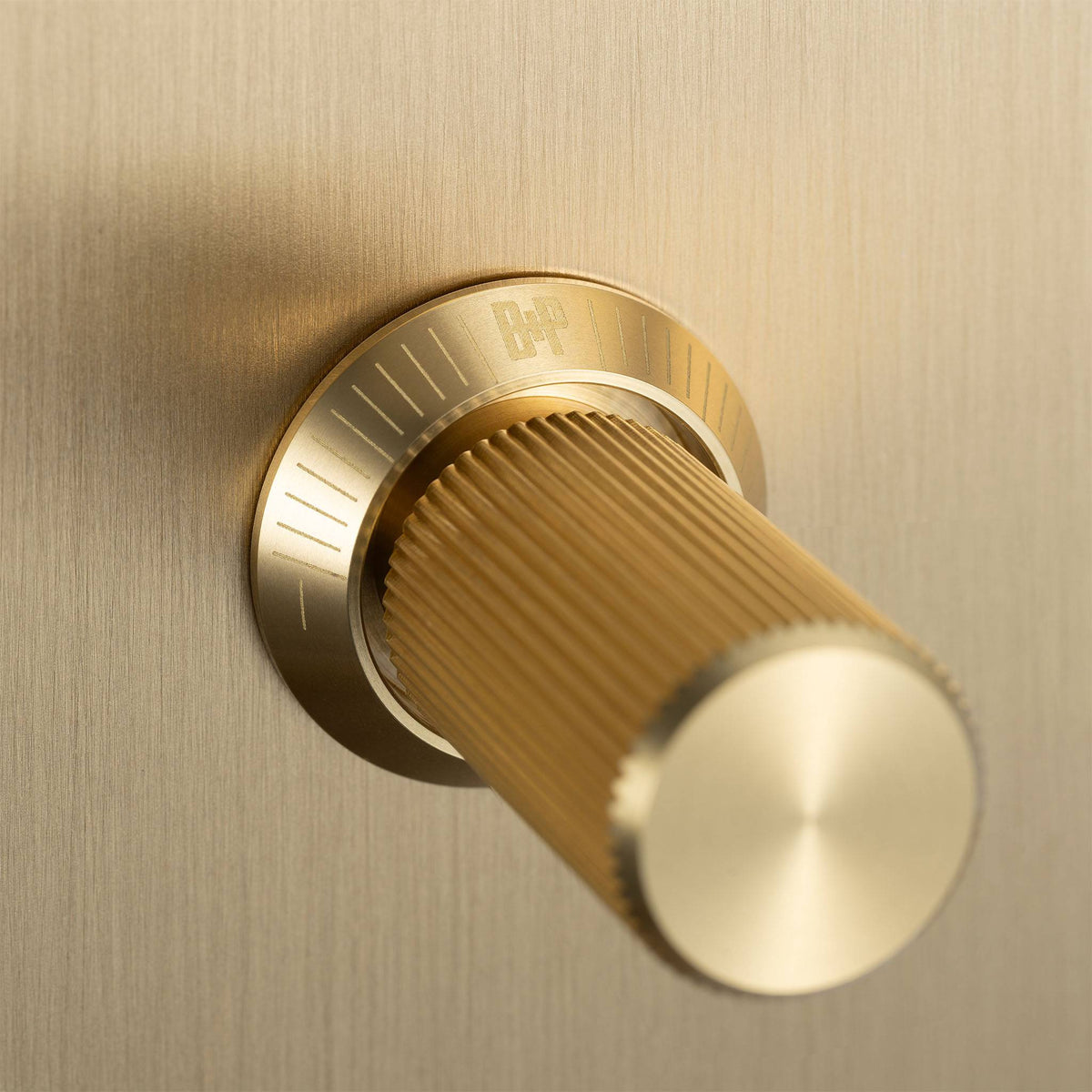 Close up of a brass dimmer switch with a ribbed cylindrical knob and a circular base with markings