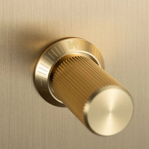 Close up of a gold cylindrical knob with a ribbed texture and a circular base with markings