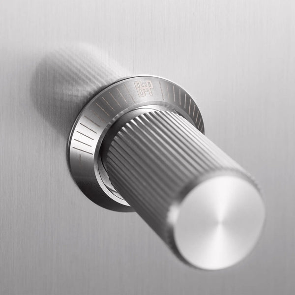 Close up of a silver metal knob with a textured grip and a circular base with etched markings
