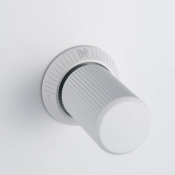 White rotary knob with a textured grip and a silver base with markings and a logo