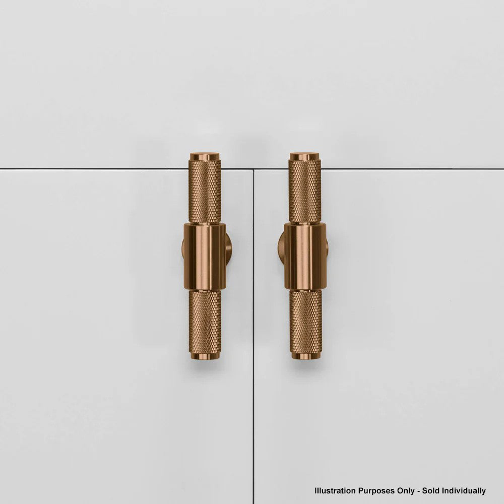 Two knurled brass cabinet handles on white cabinet doors