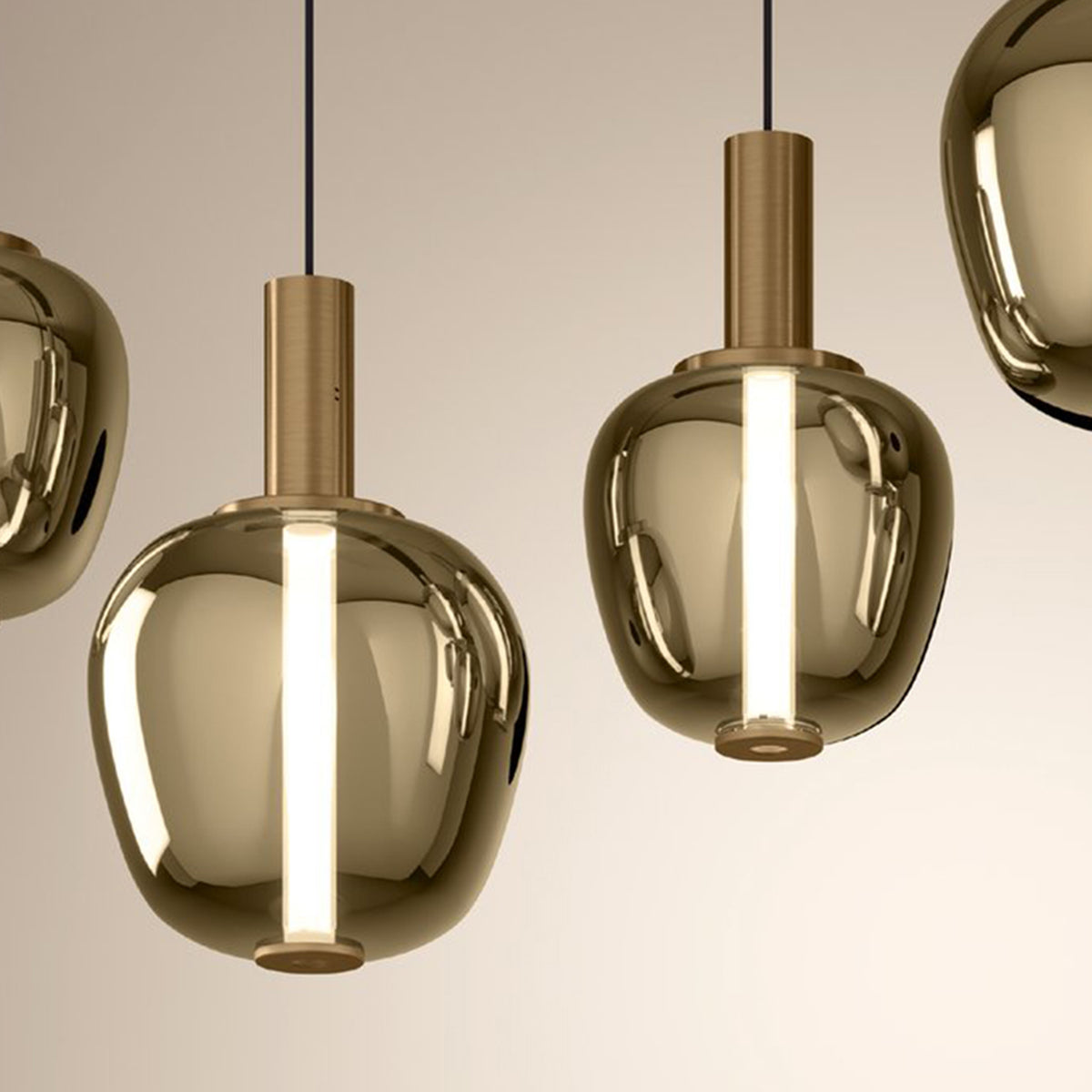 Four modern pendant lights with reflective gold-toned glass shades and bright vertical light sources.