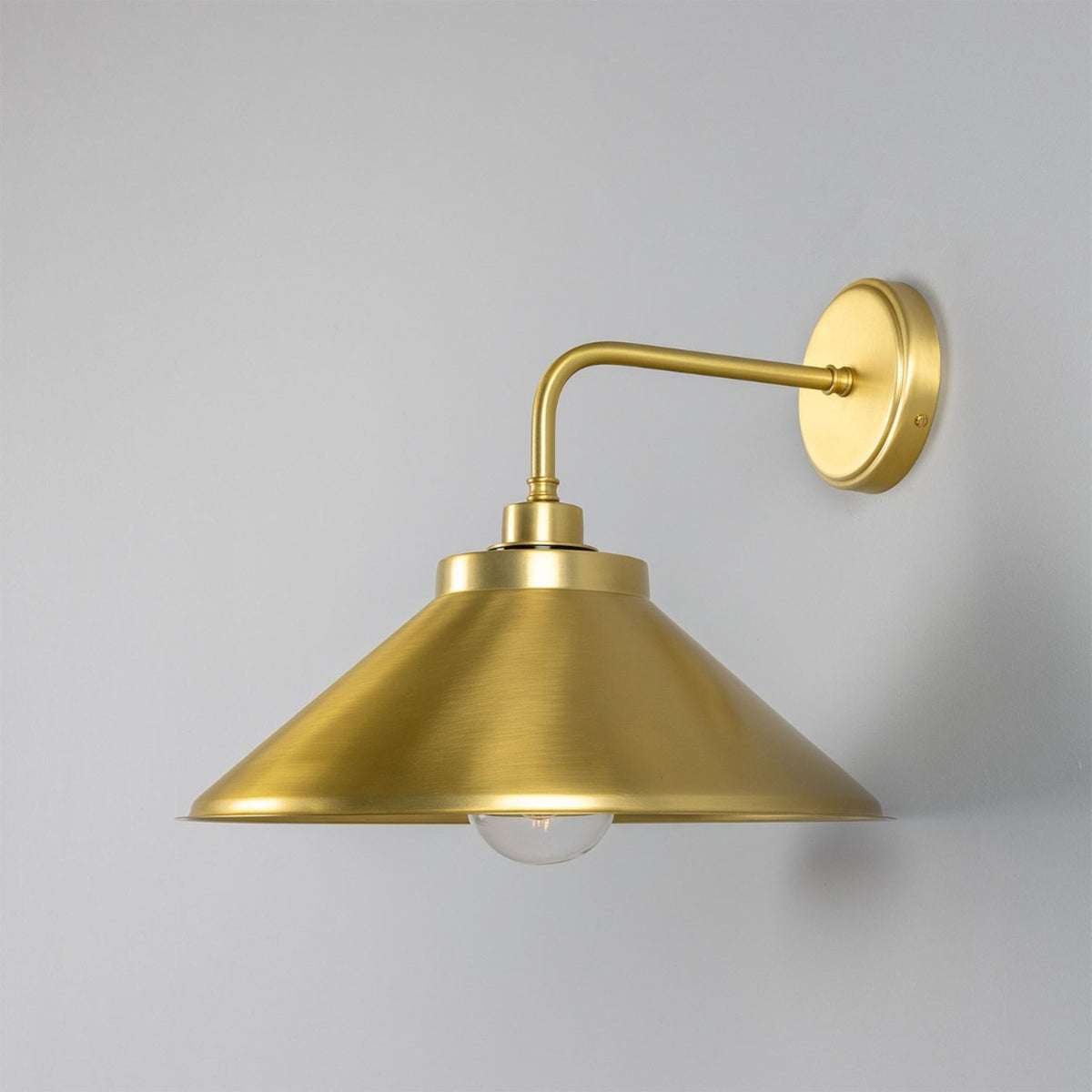 Mullan Nerissa IP65 satin brass bathroom wall light with a conical shade and clear glass bulb