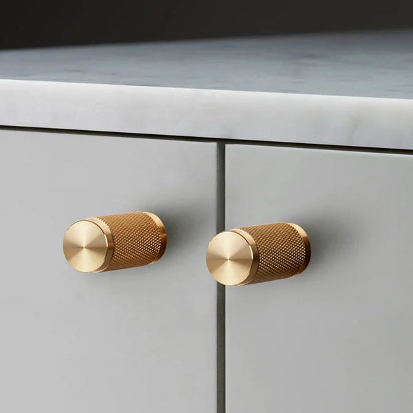 Buster + Punch Knurled Furniture Knob Set In Solid Brass on light gray cabinet