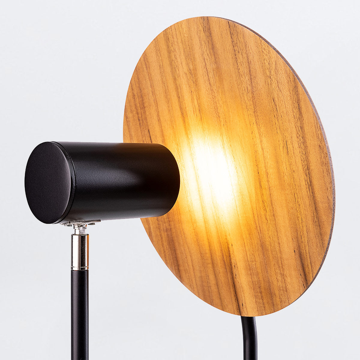 Accord Dot Natural Teak Wood Veneer Table Lamp with light shining on a wooden disc