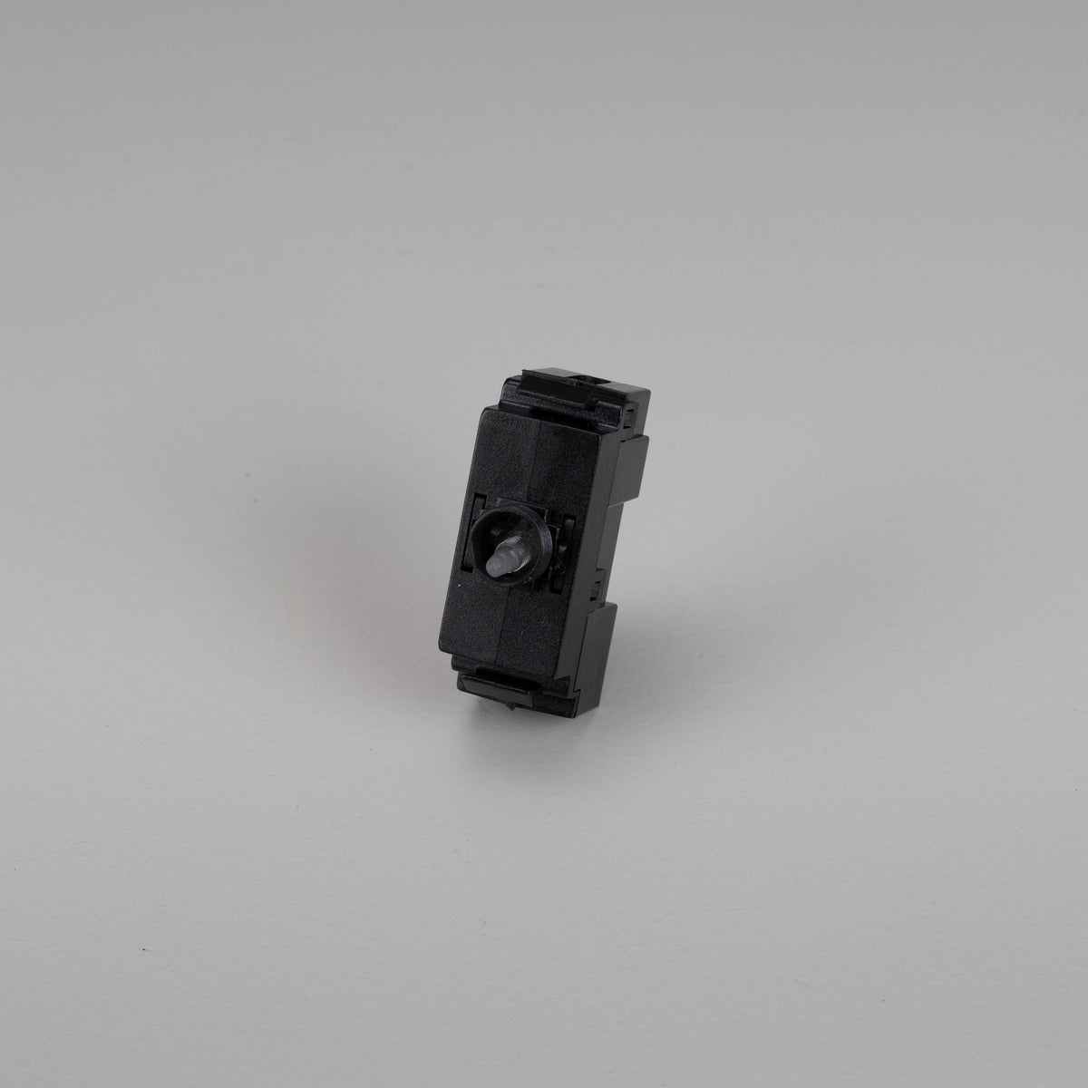 Black plastic electrical component with a small grey knob on a white background